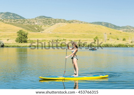 Young woman learning how to paddleboard on small pond.