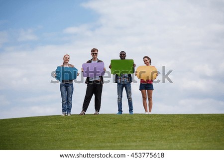Happy people in full length isolated on blue sky. Picture of best friends holding papers with space for any ideas on picnic.