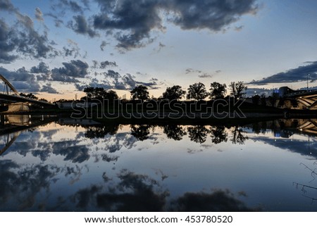 Cloudy vibrant sky and smooth reflection in the river.