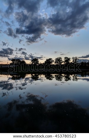 Cloudy vibrant sky and smooth reflection in the river.