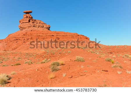 Mountainscape of red rock formation with curiously sombrero-shaped, blue sky and cloud in Utah. Mexican Hat is a census-designated place on the San Juan River in south-central San Juan County, Utah,US