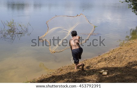 Asian fisherman throwing fishing net under the sunlight