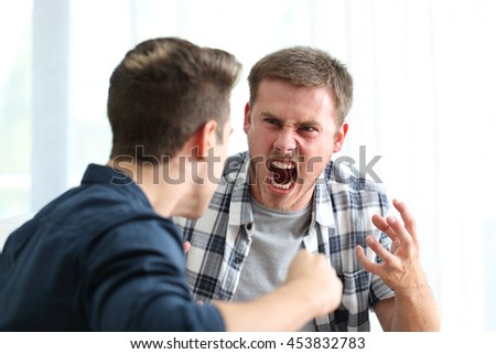 Two angry friends or roommates arguing and threatening in the living room at home Royalty-Free Stock Photo #453832783