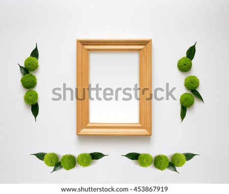 Wooden frame with empty space with decoration of chrysanthemum flowers and ficus leaves on white background. Overhead view. Flat lay.