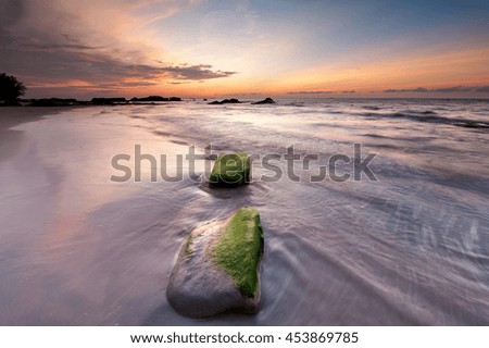 rock couple on the beach with stunning sunset sky. image contain soft focus and blur.