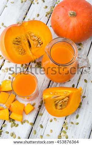 fresh orange pumpkin and pumpkin juice on a white wood background, rustic style, selective focus