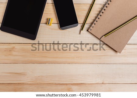 Business workspace with notebook pencil tablet and smartphone on wood table.