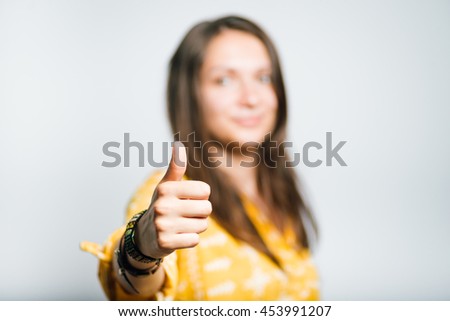 pretty girl shows sign like thumbs up, studio isolated