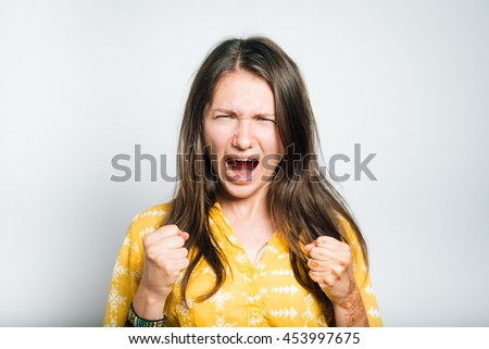 pretty girl screams and rejoices the victory with his fists, studio isolated