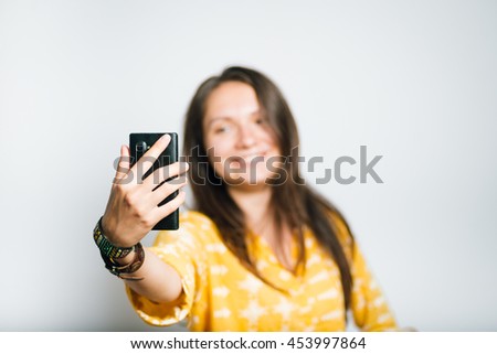 cute girl making a fun selfie photo on the phone, studio isolated