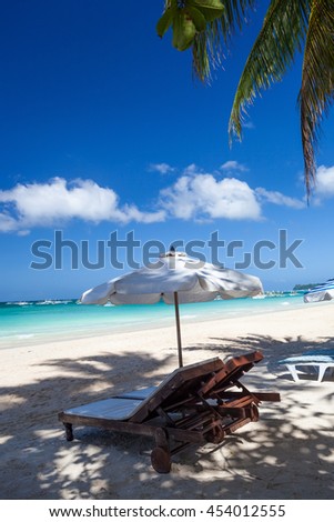 Sun umbrella and sunlongers on sandy tropical beach with white sand and turquoise sea water Royalty-Free Stock Photo #454012555