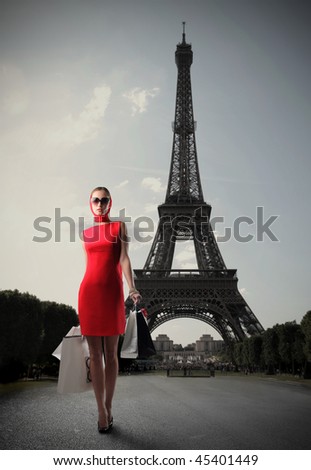 Woman in red dress carrying some shopping bags with the Eiffel tower on the background