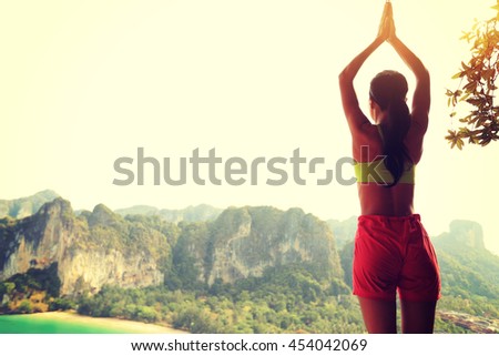 young healthy woman practice yoga on mountain peak cliff