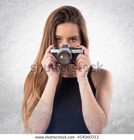 Young girl holding a camera over textured background