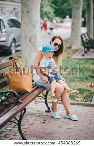 Fashion mother and her little son posing in a park