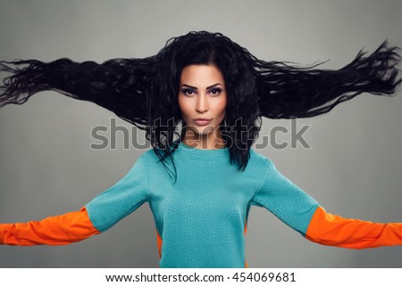 beautiful young model girl Asian appearance, with its chic black bushy hair scatter in different directions is large pieces on a gray background outstretched hand