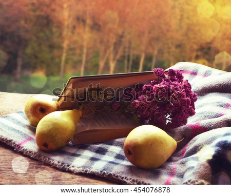 Book and pears on the table in the autumn park.
