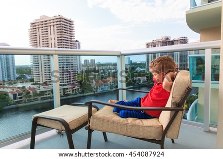 little boy relax on the balcony looking at cityscape
