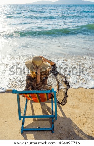 Young woman in hat sitting on tropical beach