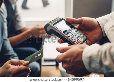 Close up of a card payment being made betweem a man and a waiter in a cafe.