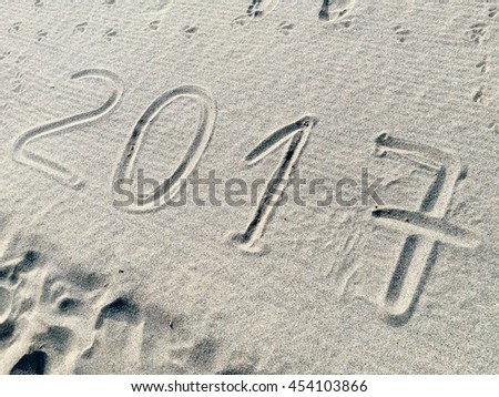 A shot of the year 2017 /numbers) engraved in the sand of a beach