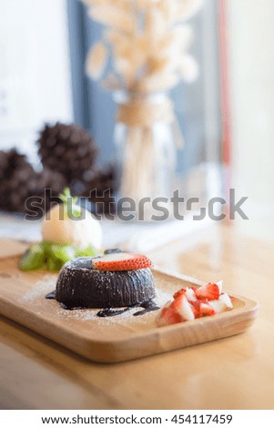 chocolate lava cake with vanilla ice cream and strawberry. chocolate lava on wood plate. Hot chocolate pudding with fondant centre.(selective focus)