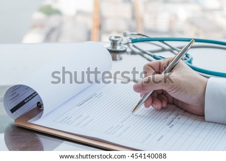 Physician doctor writing on medical health care record, patients discharge, or prescription form paperwork in hospital clinic