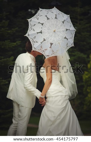 Bride hides her kiss behind a white umbrella