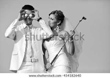 Black and white picture of newlyweds posing with golf stuff