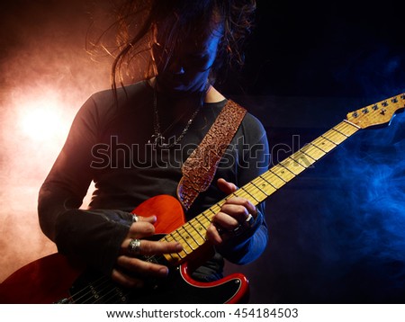 The guitarist plays solo. Close-up. Dark background. Smoke