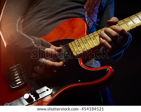The guitarist plays solo. Close-up. Dark background. Smoke