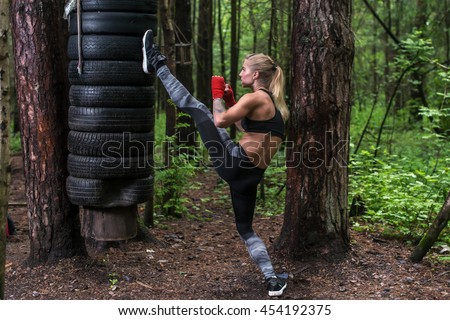 Woman practising kickboxing performing a leg axe kick working out outdoors. Royalty-Free Stock Photo #454192375