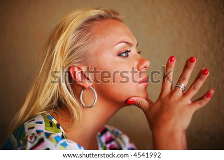 Portrait of a beautiful blond woman thinking with chin on hands. Shallow DOF, focus on eye.