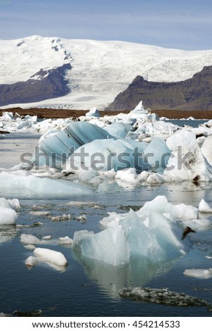A stunning landscape of a lagoon in Iceland, with the ice cold water and small icebergs, and snowy mountains in the background.