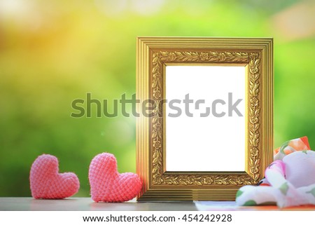 Golden frame with heart on wooden table