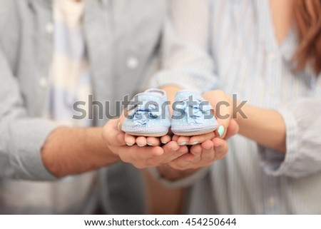 Husband and pregnant woman holding baby shoes, closeup Royalty-Free Stock Photo #454250644