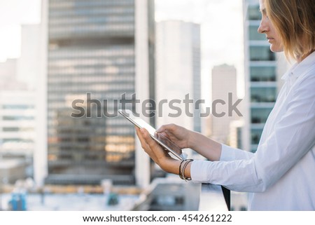 Businesswoman works on city background, young woman holding and  using modern digital tablet,  Flare light, Shallow DOF.