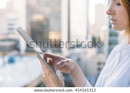 Close-up of young woman checks messages on the tablet, woman using digital tablet on city background, comfortable workplace, Shallow DOF.