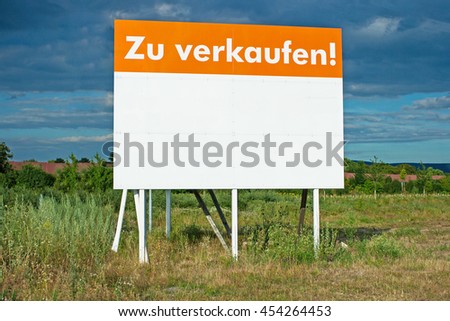 For Sale text  in German. Huge billboard for land sale  to build a house or manufacture on green grass background