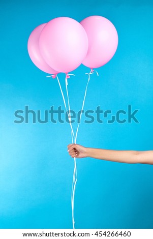 Unrecognizable girl holding three pink air balloons on blue background.isolate.Concept.