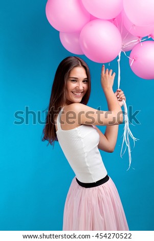 candid cheerful girl with pink balloons on blue background.Studio shot.