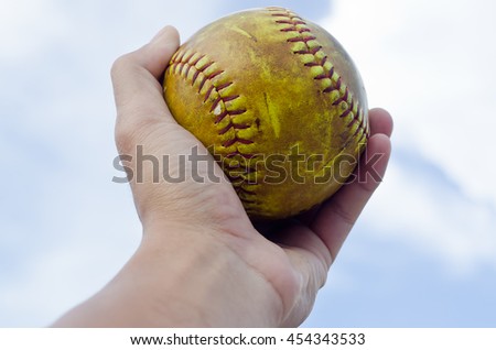 softball in hand ,sky background
