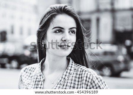 Young girl walking the streets of the big city.Beautiful brunette with piercing eyes.Wind in hair.Fashion portrait of stylish trendy woman.Outdoor portrait of beautiful teenage in black and white.