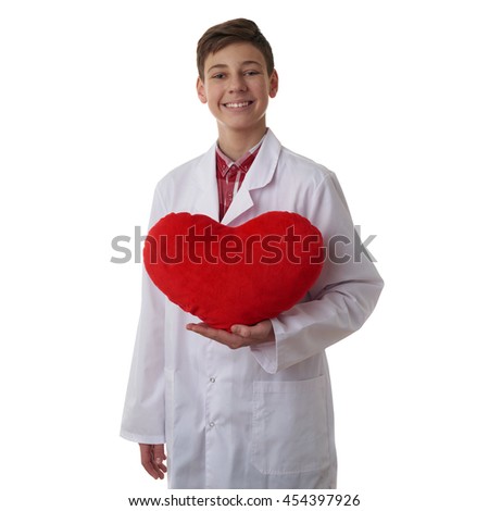 Cute teenager boy wearing white lab medic coat with red plush heart over white isolated background as science, medicine, healthcare concept