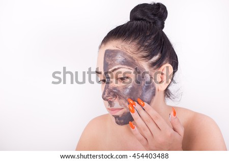 Pretty young woman applying mask to face skin. Isolated on white background