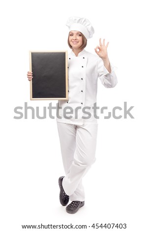smiling female chef, cook or baker with blackboard showing an okay sign isolated on white background. proposing restaurant menu. advertisement gesture