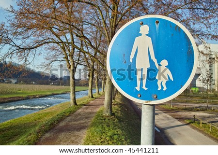 allee in autumn on river dam with traffic sign