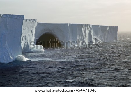 Waves breaking on gigantic tabular iceberg in the Drake Passage near Antarctica (two miles long, probably broke off from the Ross Ice Sheet) Royalty-Free Stock Photo #454471348