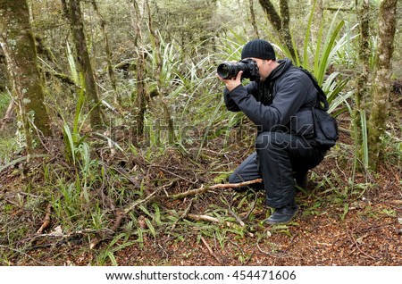 Professional nature, wildlife and travel photographer shooting outdoors during on location photo assignment in Tongariro National Park rain forest, New Zealand. Real people.Copy space.