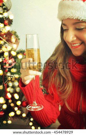 Young woman with glass of champagne with christmas tree on background
